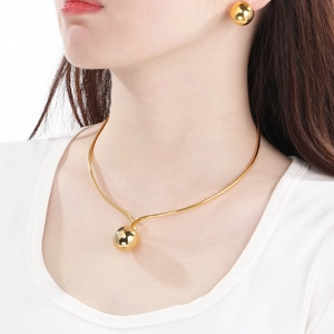 Close-up of a model wearing a golden hollow ball collar necklace and matching stud earrings