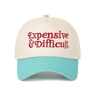 Detail of red Expensive & Difficult embroidery on a two-tone beige and mint green cap