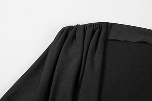 Detailopname van elegante geplooide details en gerimpelde zwarte stof op een strakke jurk