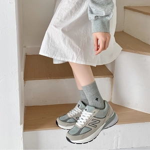 Close-up of grey vertical striped cotton socks with bee embroidery worn with sneakers