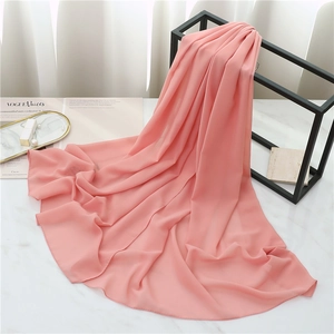 Pink chiffon scarf draped on a black metal stand with magazine and marble background