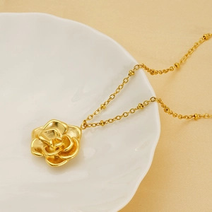 Elegant 18K gold plated stainless steel camellia flower pendant necklace on white ceramic tray