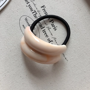 Macro shot of double-curved cream resin accessory on high-elasticity black hair tie