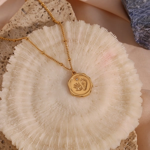 Détail du pendentif doré avec empreintes de bébé et un petit cristal scintillant élégant