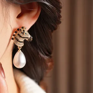 Vintage gold zebra stud earrings with black and white rhinestones and a large pearl drop