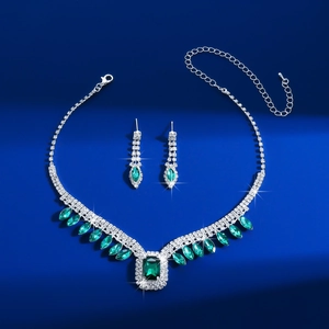 Detailed view of silver necklace and emerald earrings set with sparkling square crystals
