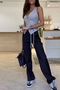 Détail d'un gilet sans manches gris à lacets et d'un pantalon large noir sur modèle