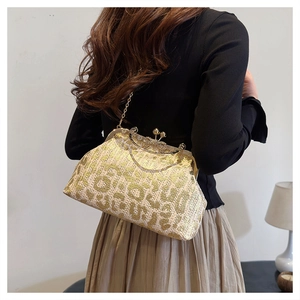 Detailed view of the woven evening clutch featuring a gold bead clasp and metal chain strap