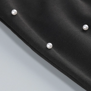 Gros plan de perles blanches serties sur le tissu noir d'une robe de soirée chic