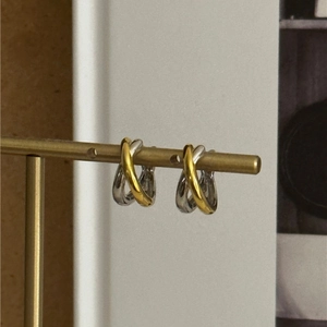 Detail of interlocking gold and silver rings on a high-polish geometric hoop earring