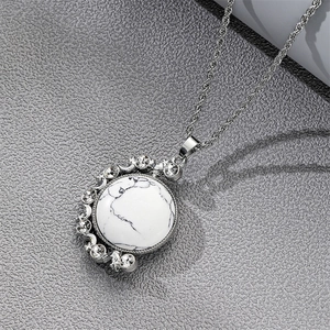 Détail de la chaîne torsadée argentée avec pendentif lune en turquoise blanche et strass