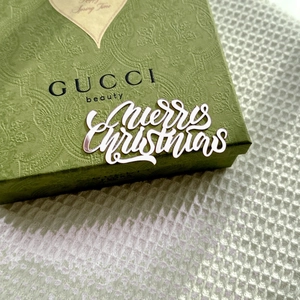 Close-up of green festive gift box featuring white Merry Christmas acrylic cake topper