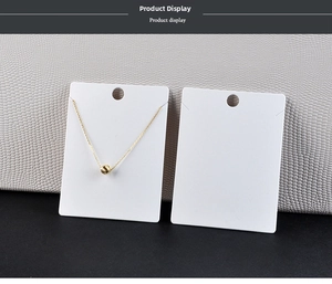 Detail of a minimalist gold sphere pendant necklace displayed on white jewelry cards