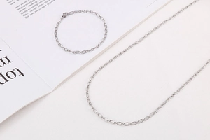 Detailed flat lay of silver minimalist oval link chain necklace and bracelet set