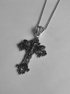 Macro shot of gothic cross necklace with skull and moth wings in vintage silver