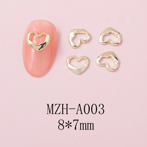 Macro detail of 8x7mm hollow heart nail art charms in golden metal finish