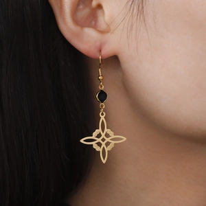 Golden S-shape Celtic knot earrings with black round gemstone on a model's ear