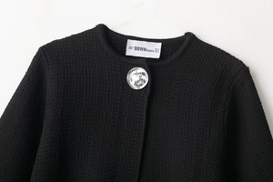 Detail of silver irregular metal button and round neck on black knit cardigan jacket
