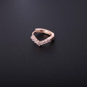 Close-up of rose gold V-shaped hoop earring with zircon inlay on a dark textured background