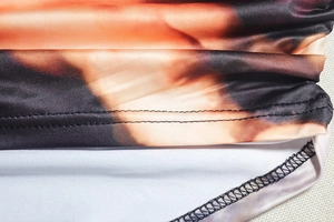 Detail of double-needle hem stitching and abstract angel print on elastic knit top