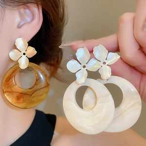 Detail view of the brushed metal flower stud and the large acrylic resin hoop earring