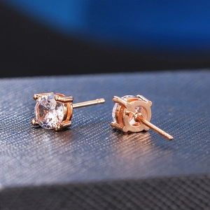 Macro shot of rose gold four-prong round zircon earrings on a blue jewelry box