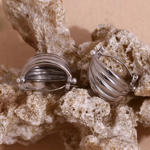 Macro shot of silver twisted hoop earrings with small pearls on natural rock background