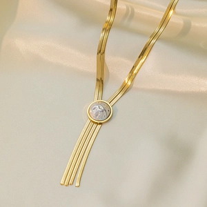 Detail of 18K gold-plated snake chain necklace with shell pendant and flowing tassels