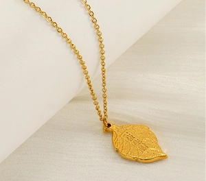 Macro detail of gold leaf pendant with Chinese characters on fine O-chain necklace