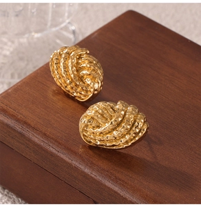 Vue macro de boucles d'oreilles en acier titane doré avec texture spirale 3D