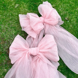 Three large pink pleated tulle bows for wedding backdrops and outdoor party decorations