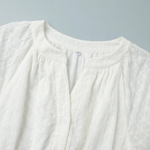 Détail du col en V avec broderie de cœurs et boutons sur cette robe blanche