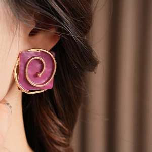 Close-up of vintage purple square earrings with golden spiral design worn by a model