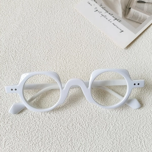 Top view of thick white square frames with black rivet details on textured surface