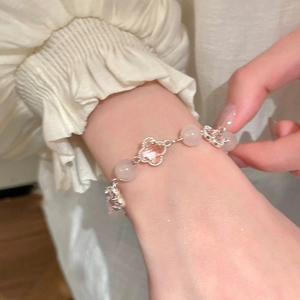 Close-up of pink crystal clover beaded bracelet worn on wrist with elegant lace cuff