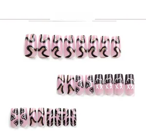 Detail view of long coffin press-on nails with pink, black, and gold glitter heart patterns