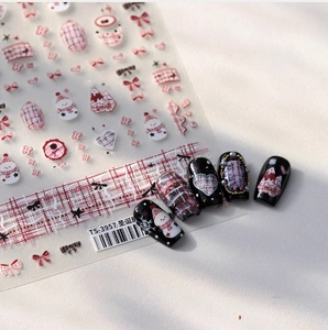 Detail of Christmas nail stickers with snowman and bow patterns on black fake nails