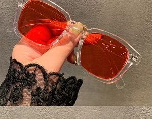 Detail shot of transparent frame sunglasses with orange lenses showing temple size 21-148