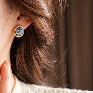 Close-up of vintage 18K gold plated earrings with iridescent dark shell on a female model