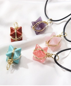 Flat lay of star-shaped crystal pendants in five colors wrapped in gold wire with black cords