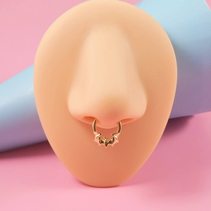 Close-up of golden bat septum ring made of stainless steel on a silicone nose model