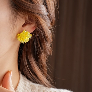 Close-up of yellow beaded square earrings with crystal clusters worn on a model ear