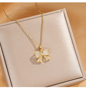 Détail du pendentif nœud doré serti de zircons sur un écrin à bijoux de luxe