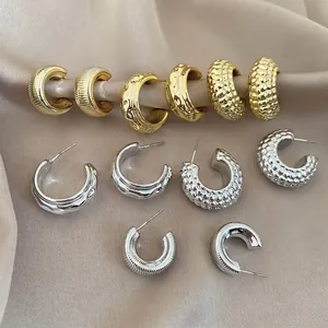 Set of acrylic textured C-shaped stud earrings in gold and silver finish on silk