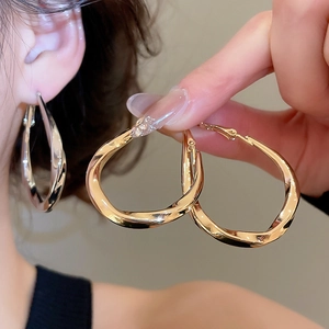 Detail view of twisted geometric hoop earrings in gold and silver mirror finish