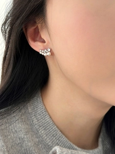 Detail shot of elegant silver needle earrings with cubic zirconia and pearls on a model
