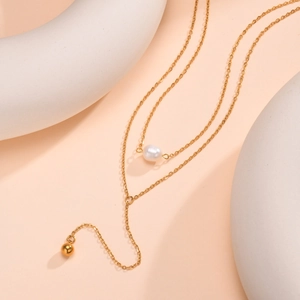 Detail view of gold layered Y-necklace with pearl pendant and polished metal ball drop
