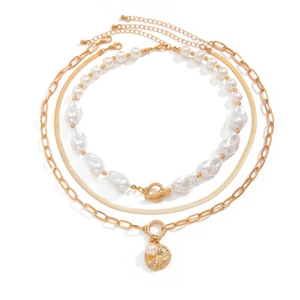 Detail of layered gold necklaces with baroque pearl and round embossed pendant