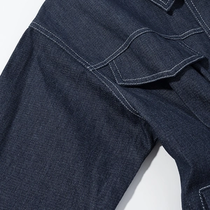 Macro detail of dark blue denim dress featuring white contrast stitching and flap pocket