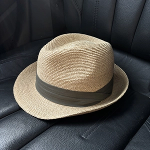 Detailed close-up of straw fedora with olive green band on leather car seat background
